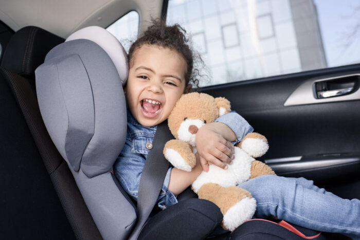 child sitting in a car seat with her teddy bear
