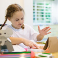 LITTLE GIRL MAKING A SET OF JUNGLE ANIMALS AS CRAFT PROJECT