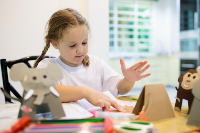 LITTLE GIRL MAKING A SET OF JUNGLE ANIMALS AS CRAFT PROJECT