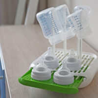 3 baby bottles and nipples on a bottle drying rack