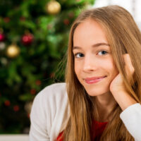 15 year old girl with christmas tree in the background