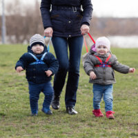 Mom holding twins on harnesses