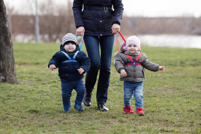 Mom holding twins on harnesses