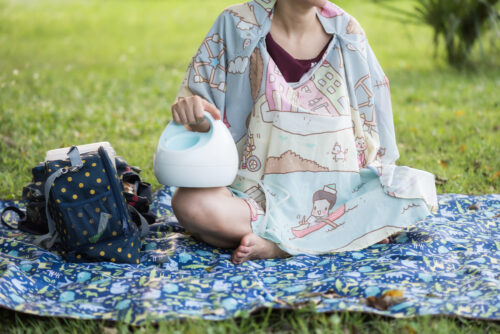 woman sitting outside pumping with breast pump bag