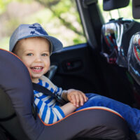 Smiling boy in baseball cap in car seat