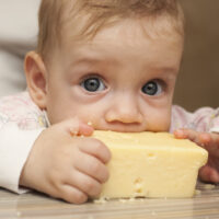 baby taking a bite out of cheese