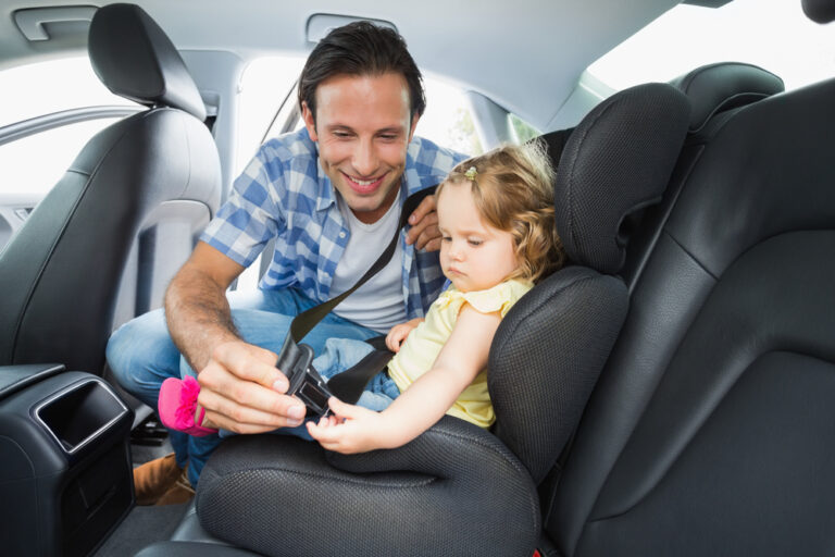 Dad strapping baby girl in car seat
