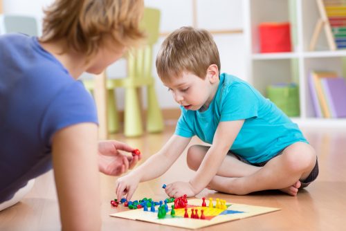 Mother and her son playing in board game on floor in nursery