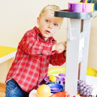 toddler boy playing with a play kitchen