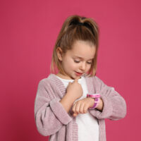 Little Girl Wearing Watch with Pink Background