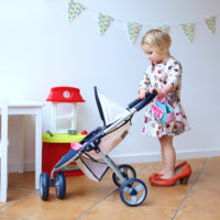 Little girl in high heels with baby stroller