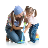 Little girl with mom using vacuum