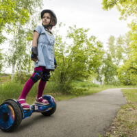 Little girl standing on hoverboard in park