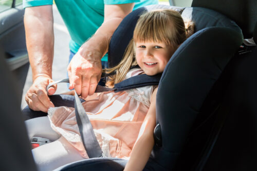 toddler getting buckled into a car seat