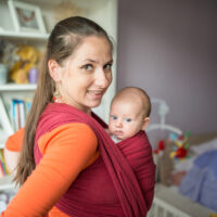 Close up of petite mom with baby in baby carrier