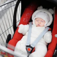 small baby in a car seat in a shopping cart