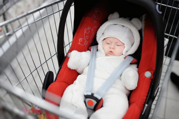 small baby in a car seat in a shopping cart