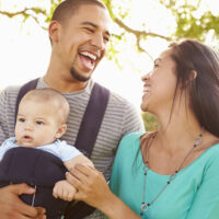 Parents laughing with baby in carrier