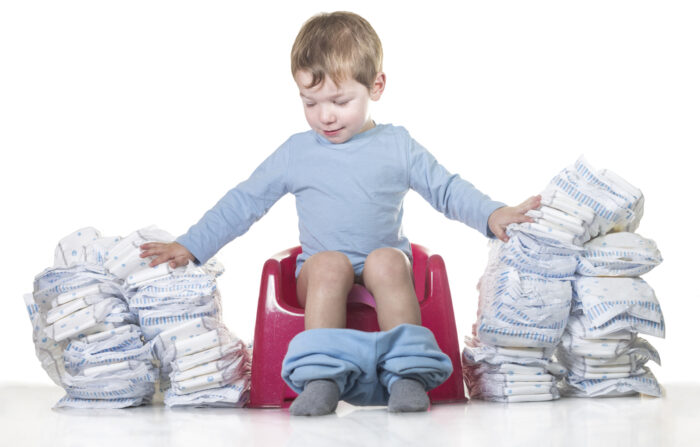 child sitting on potty seat with a bunch of diapers