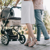 parents pushing baby in stroller with fan on it