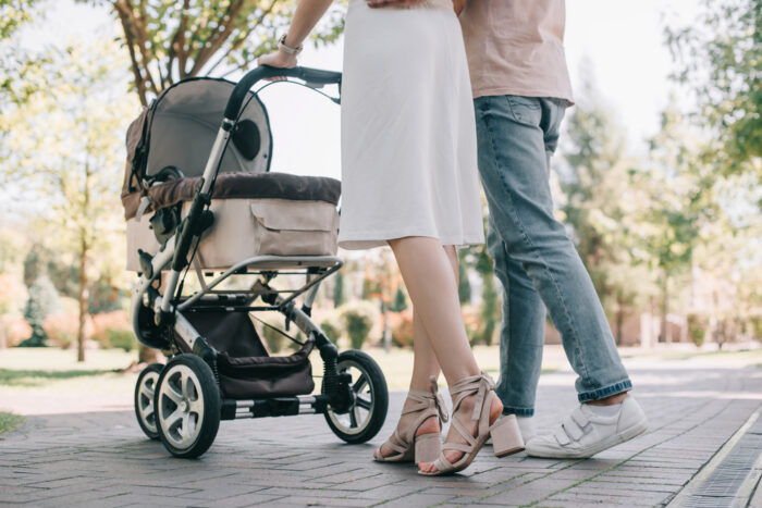 parents pushing baby in stroller with fan on it