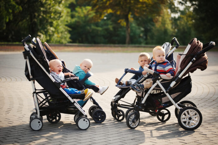 children sitting in strollers outside