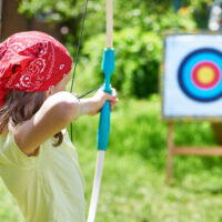 Girl in red bandana shooting a bow