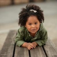 Little Girl Laying on Bench with Curly Hair