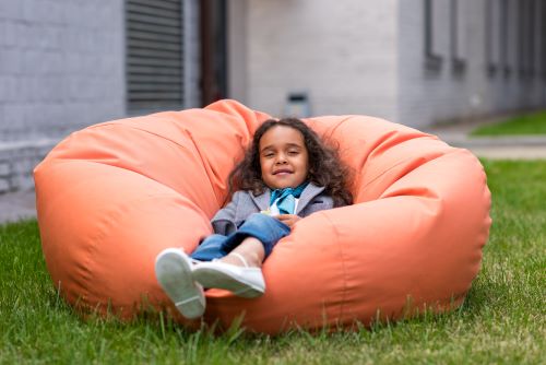 little girl on bean bag chair in the grass