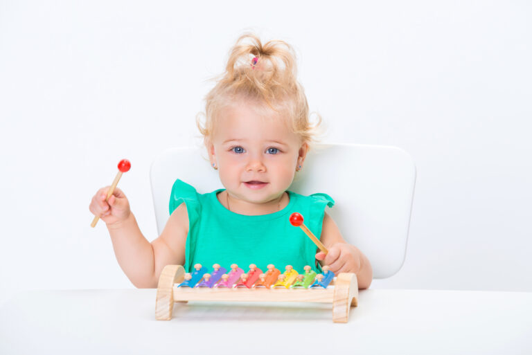 Smiling blonde girl playing xylophones