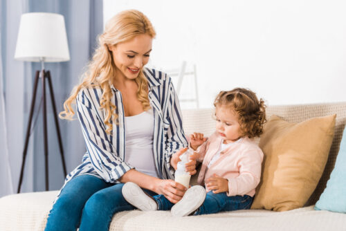 Mom and toddler sitting on couch with toddler drink