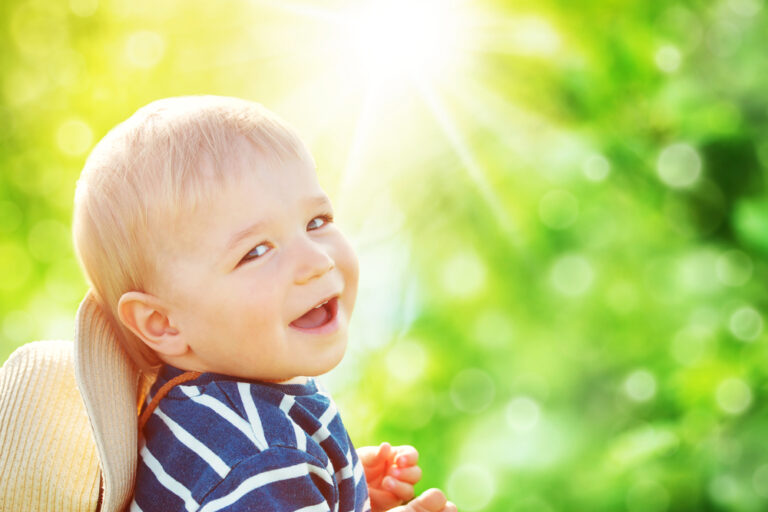 little boy laughing in the sun outside