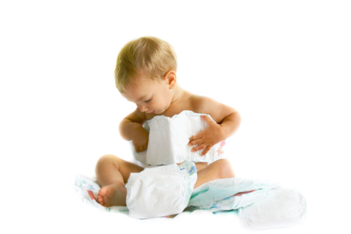 baby playing with huggies diapers on white background