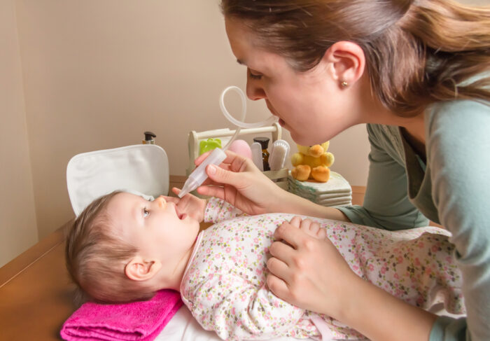 mom getting boogers out of a baby\'s nose