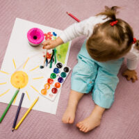 Little Girl Sitting On Floor Painting a Picture