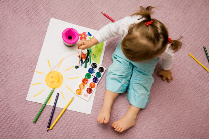 Little Girl Sitting On Floor Painting a Picture