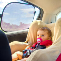 baby in car seat with sun shade on window