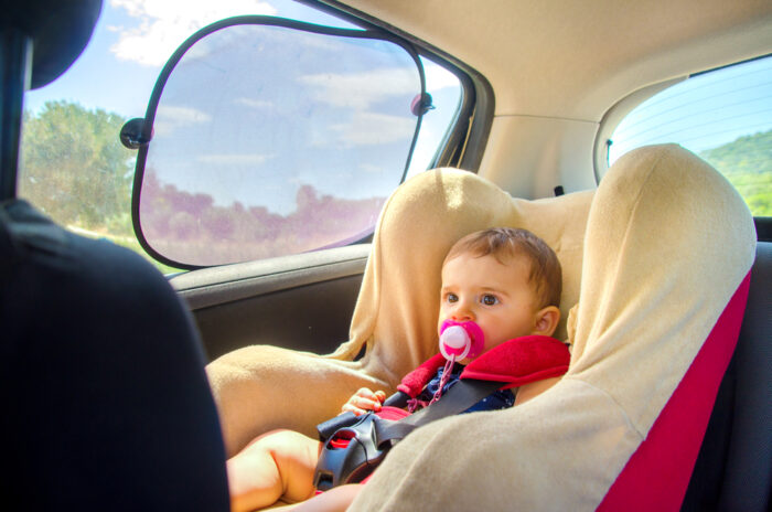 baby in car seat with sun shade on window