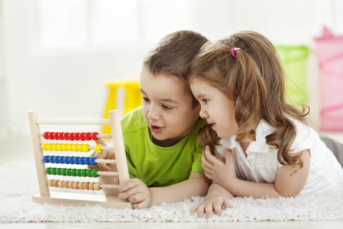two small children playing with abacus math toy and having fun