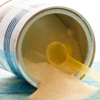 soy baby formula can with scoop spilling onto table