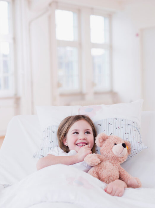 smiling child getting ready to sleep in their own bed at night