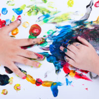 Closeup of little children hands doing finger painting with vari