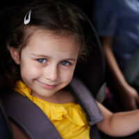 Smiling Girl Belted in Booster Seat