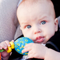 Blue-eyed baby sitting in car seat