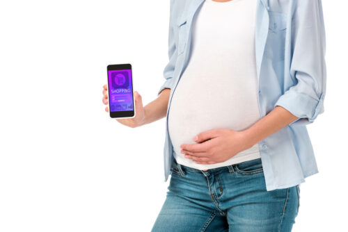 pregnant woman holding phone with baby registry app on a white background