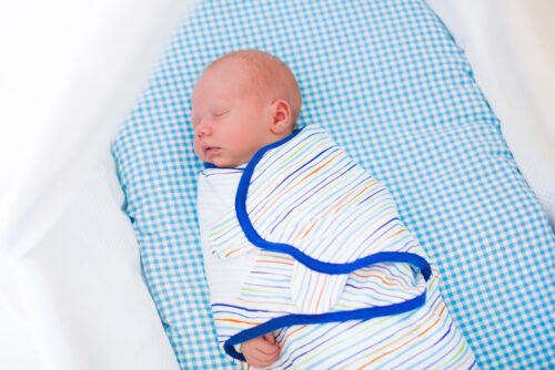 baby boy in bassinet wearing baby swaddle