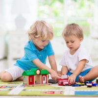 two young boys playing with toys on a carpet playmat