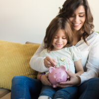 mother and daughter putting money into a piggy bank