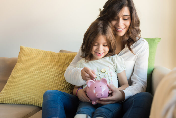 mother and daughter putting money into a piggy bank