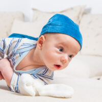 Cute 2 months old baby boy at home trying to roll over